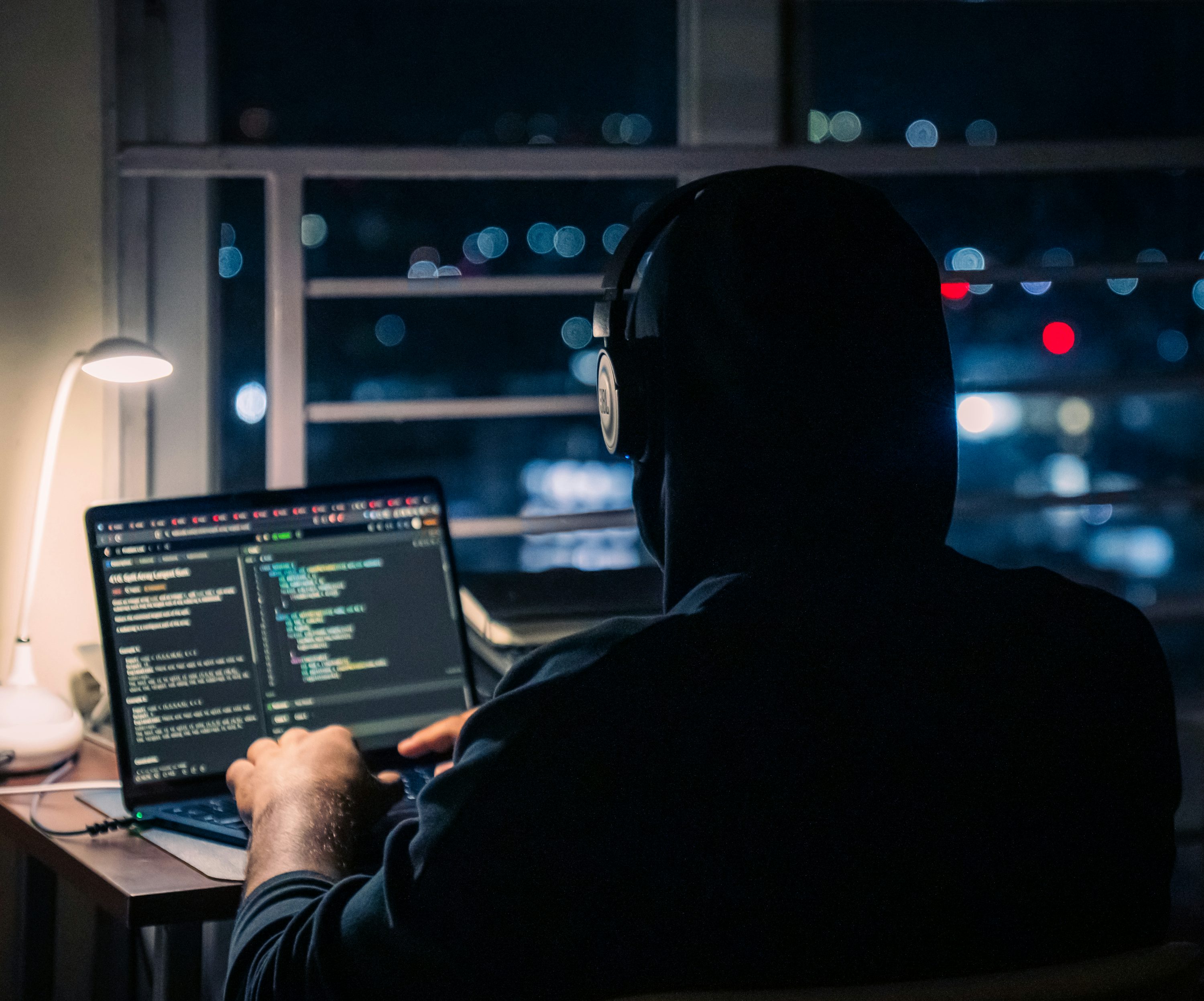 A programmer using a laptop at a desk at night.