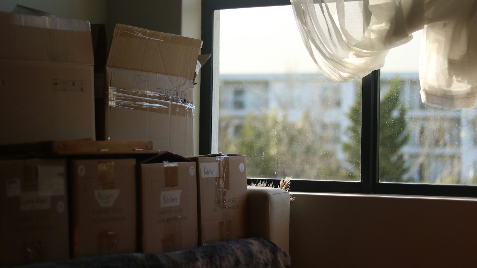 A room with moving boxes stacked by a window