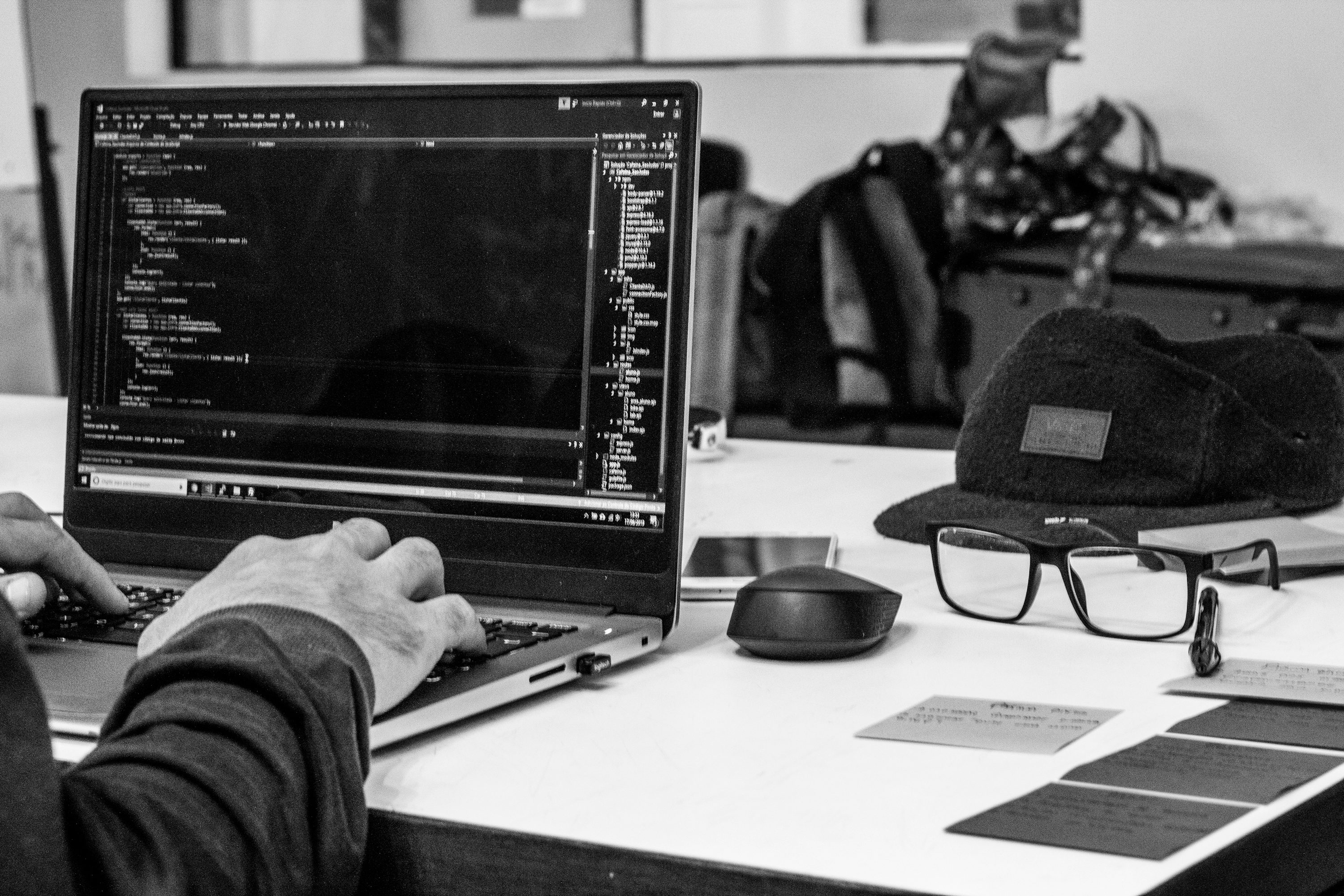 A laptop displaying code beside a camera on a desk.