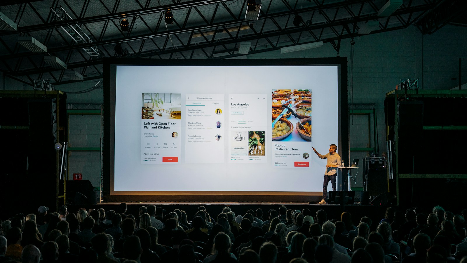 A founder presenting slides to a small audience in a dim room