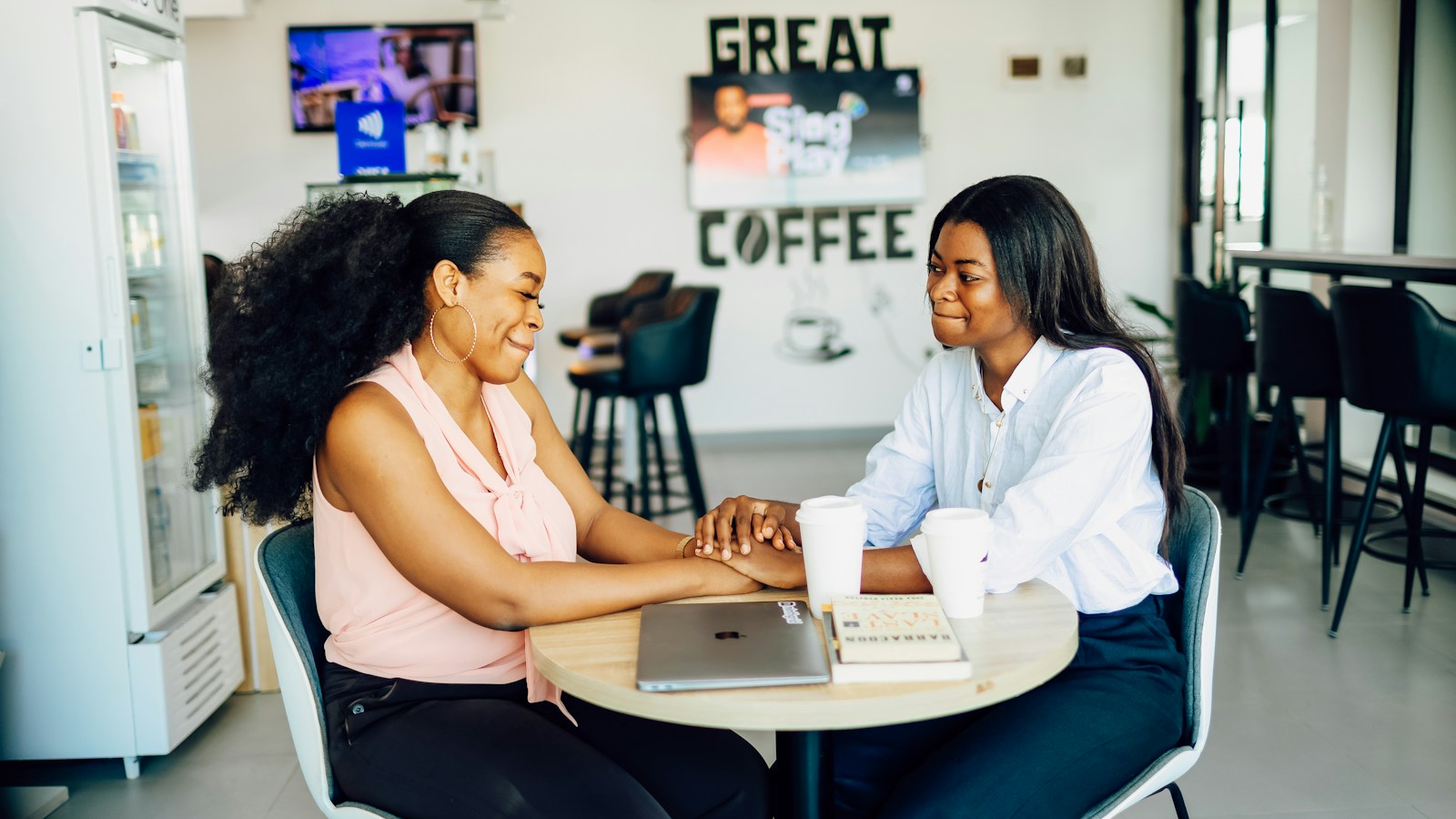 Two women sitting at a table with a laptop, talking