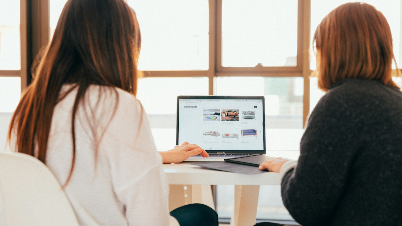 Two women talking while looking at a laptop computer